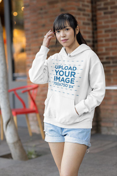 Hoodie Mockup Featuring a Young Long-Haired Woman Posing on the Street