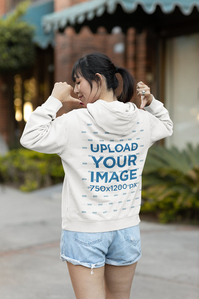 Back-View Mockup of a Cool Woman Pointing at her Hoodie