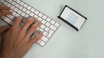 Business Card Lying in a Holder on a Desktop While a Man is Typing a Keyboard in Stop Motion