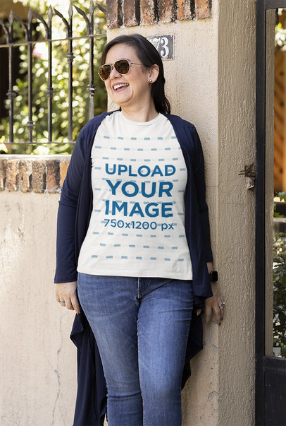 T-Shirt Mockup Featuring a Happy Woman Leaning on a Wall in the Street