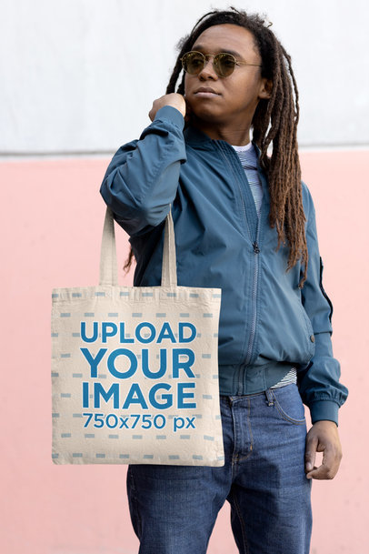 Tote Bag Mockup of a Man with Sunglasses Posing Behind a Wall 