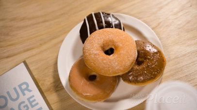 Book Video Lying on a Wooden Table Alongside a Plate of Donuts