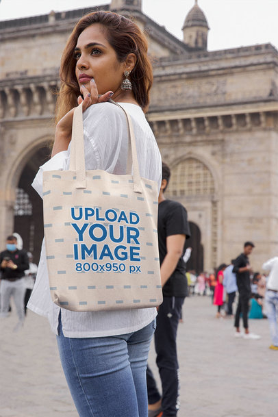 Mockup of a Woman Holding a Tote Bag Over Her Shoulder in the City 