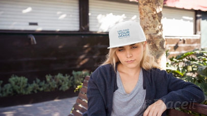 Blonde Woman Wearing a Snapback Hat Video Mockup While Sitting on a Bench Outdoors