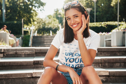 T-Shirt Mockup of a Young Woman Smiling While Sitting on Some Steps
