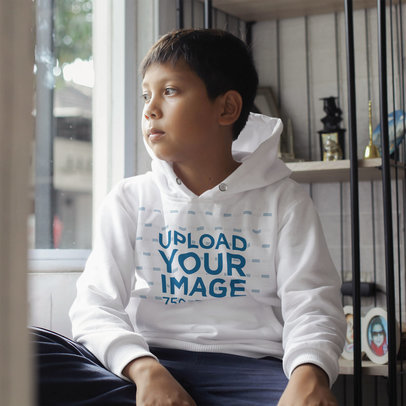 Hoodie Mockup Featuring a Thoughtful Kid Looking Through the Window