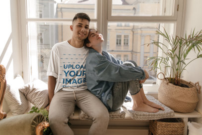 Oversized T-Shirt Mockup Featuring a Young Man and His Girlfriend Sitting by a Window