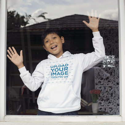Hoodie Mockup of a Funny Young Boy at the Other Side of a Window