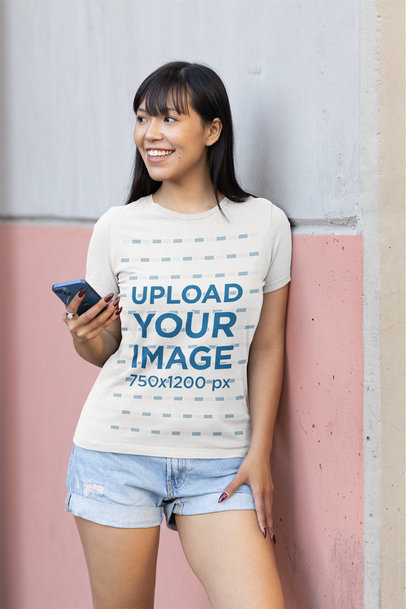 Round-Neck Tee Mockup Featuring a Woman Leaning Against a Pink and White Wall 
