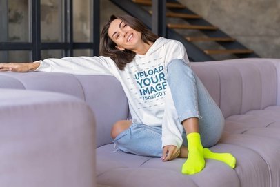 Hoodie Mockup Featuring a Happy Woman Sitting on a Comfy Couch