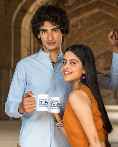 Mockup of a Couple Holding 11 oz Coffee Mugs While Posing in Front of a Temple