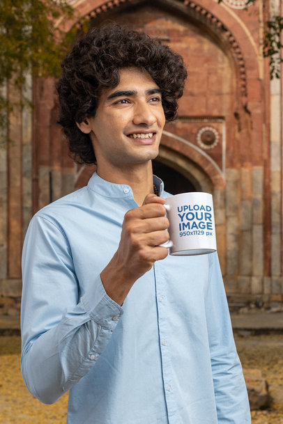 Mockup of a Happy Man Holding His 11 oz Coffee Mug While Posing in Front of a Temple