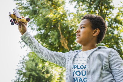 T-Shirt Mockup Featuring a Boy Playing with an Airplane Toy