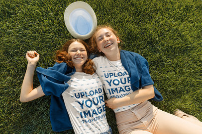 T-Shirt Mockup Featuring Two Friends Lying Happily on the Grass
