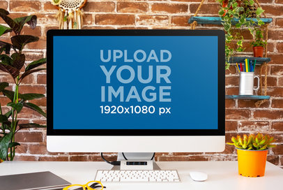 Mockup of an iMac Placed on a White Desk with a Brick Wall in the Background
