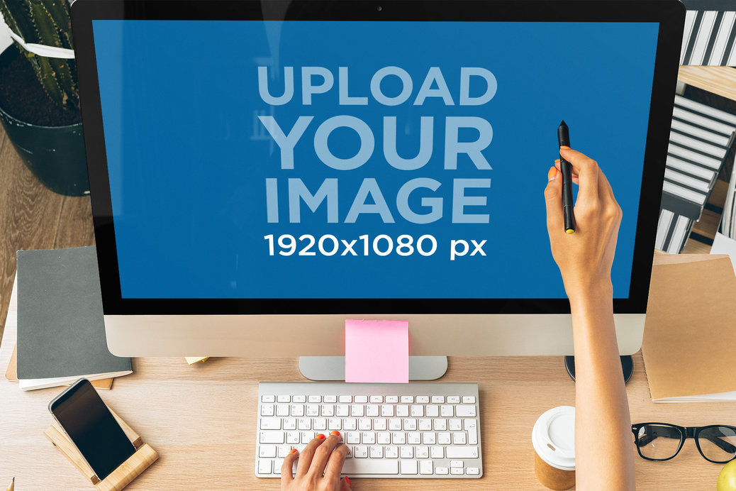 iMac Mockup Featuring a Woman's Hand Pointing at the Screen With a Pen