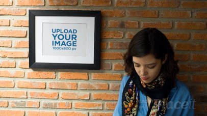 Woman Texting on her Phone While Against a Bricks Wall With a Framed Art Print Video