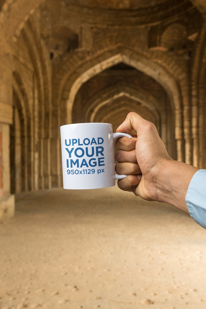 Mockup of a Hand Holding an 11 oz Coffee Mug in a Temple