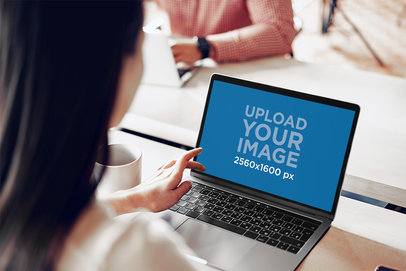 Mockup of a Woman Using a MacBook Pro in an Office