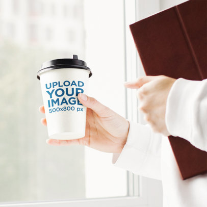 Mockup of a Woman With a White Hoodie Holding a Paper Cup