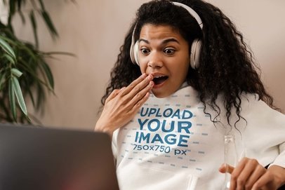 Hoodie Mockup Featuring a Surprised Woman Wearing Headphones at Home