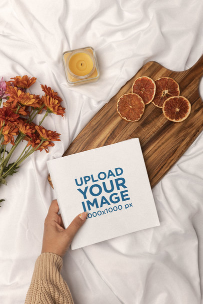 Mockup of a Square Book Being Placed on a Cute Aesthetic Setting