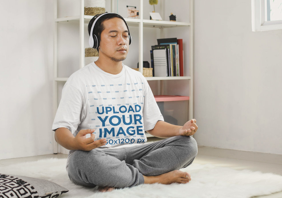 T-Shirt Mockup of Man With Headphones Doing Yoga in His Room