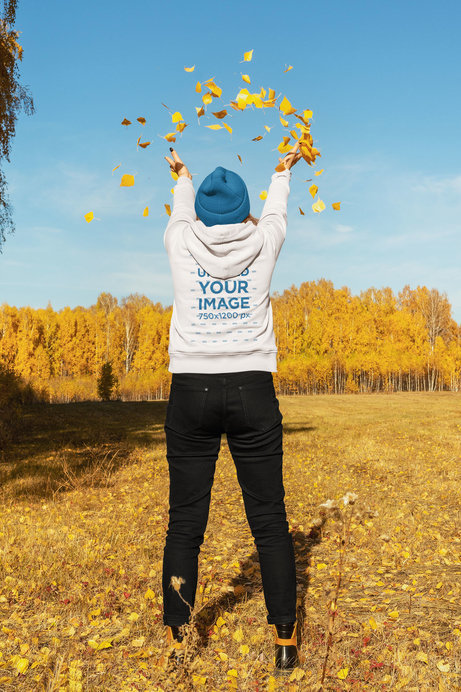 Back-View Hoodie Mockup of a Woman Playing With a Bunch of Autumn Leaves