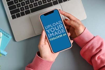Mockup of a Woman Holding an iPhone 13 at Work