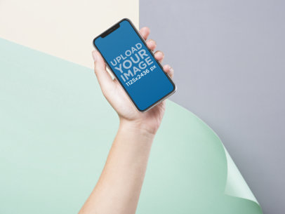 iPhone 11 Pro Mockup of a Hand Holding an iPhone Over a Colorful Background