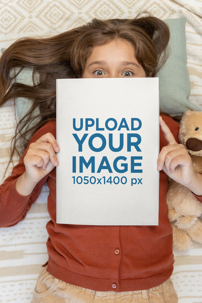 Mockup of a Girl Holding a Book While Lying in a Bed 