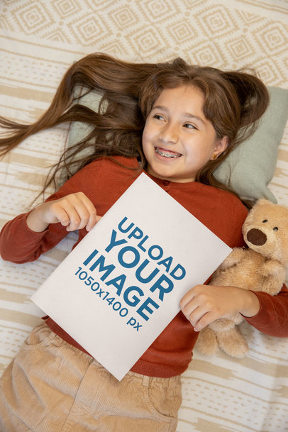 Mockup of a Girl Lying in Bed and Holding a Book and a Teddy Bear 