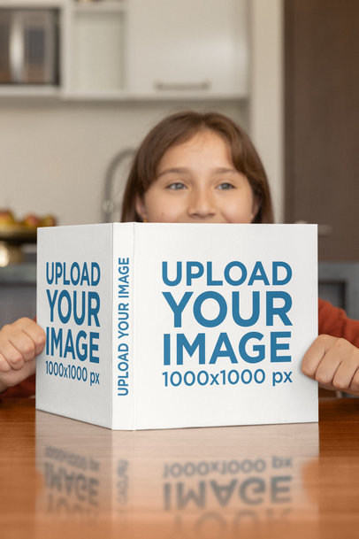 Mockup of a Girl Reading a Square Book on a Table