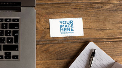 Business Card Moving in Stop Motion on a Wooden Desk Near a Laptop and a Note Pad a13869