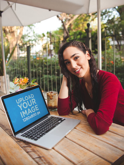 Happy Woman Sitting on a Bench Showing You a MacBook Pro Mockup a19513