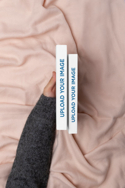 Mockup of a Hand Showing the Spine of Two Books Against a Cozy Setting
