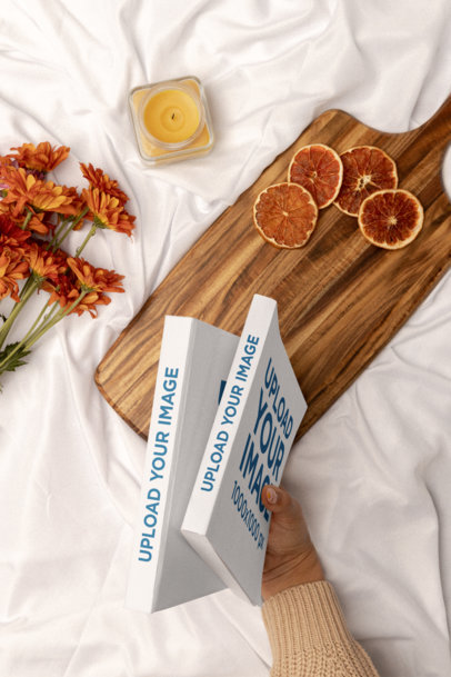 Mockup of a Woman's Hand Holding Two Books at a Picnic