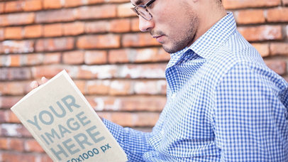 Mockup of a Cool Guy Wearing Glasses Reading a Book in Stop Motion While Sitting Down