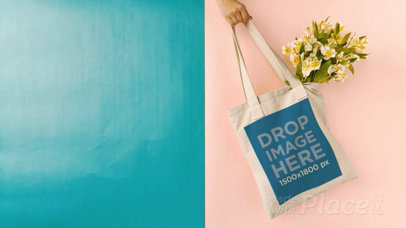 Hand Swinging a Tote Bag in Stop Motion Against Bicolored Background With Flowers a13664