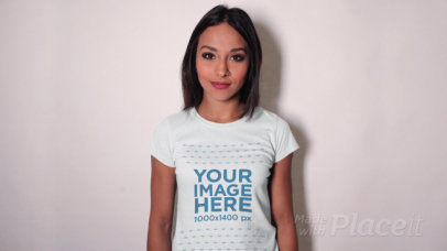 Smiling Pretty Woman Wearing a Round Neck T-Shirt Stop Motion Leaning Against a White Wall