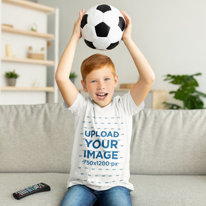 T-Shirt Mockup of a Happy Boy Lifting a Soccer Ball at Home