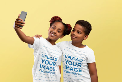 T-Shirt Mockup Featuring Two Siblings Taking a Selfie in a Studio