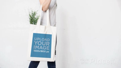 Stop Motion of a Tote Bag Being Held by a Woman Walking by a White Wall