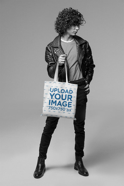 Sublimated Tote Bag Mockup Featuring a Curly-Haired Man in a Studio