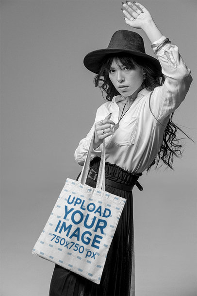 Monochromatic Mockup Featuring a Stylish Young Woman Posing with a Tote Bag at a Studio