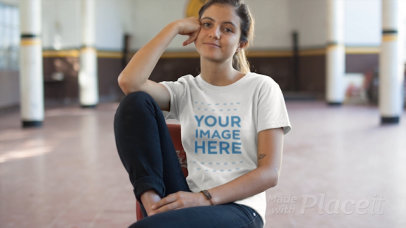 Young Smiling Girl Wearing a Tshirt Video while Sitting in the Middle of a Gym a12856