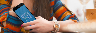 Woman Holding an iPhone 6 at the Table Mockup Wide