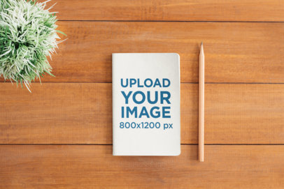 Mockup of a Book Placed Next to a Pencil on a Wooden Surface