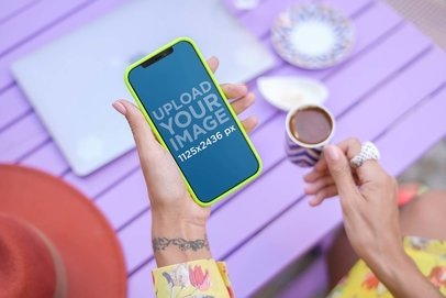 Digital Mockup of a Woman with a Wrist Tattoo Holding an iPhone 12 Pro