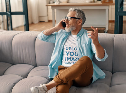 Round-Neck Tee Mockup of a Bearded Man Talking on His Smartphone at Home